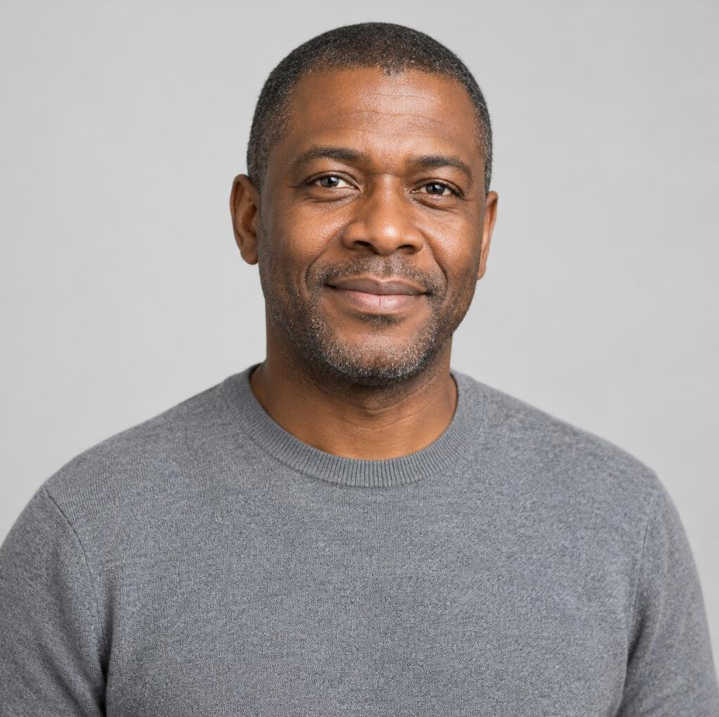 Portrait of a Black man in his forties with short hair and a grey sweater